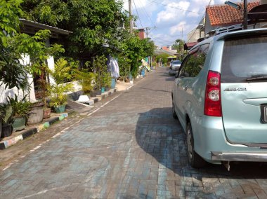 Asfaltlı yolları ve açık mavi arabaları olan bir ev. Sabahleyin görüldü