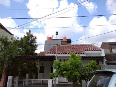 Semarang, Endonezya, 11 Temmuz 2021 - Önünde açık mavi bir araba olan Endonezya 'da beyaz bir ev