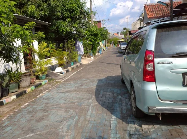 Asfaltlı yolları ve açık mavi arabaları olan bir ev. Sabahleyin görüldü