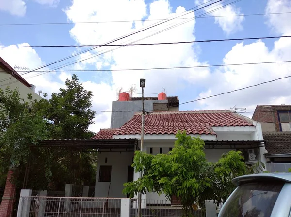 Semarang, Endonezya, 11 Temmuz 2021 - Önünde açık mavi bir araba olan Endonezya 'da beyaz bir ev