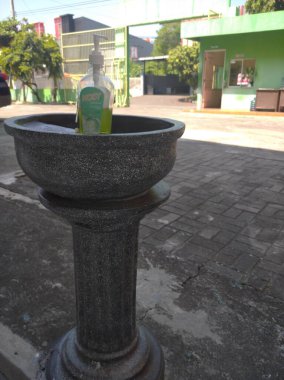 Geniş bir okul bahçesinde sabunlu el yıkama alanı.