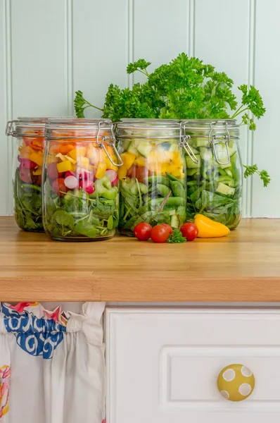 Salad in glass storage jars in kitchen.