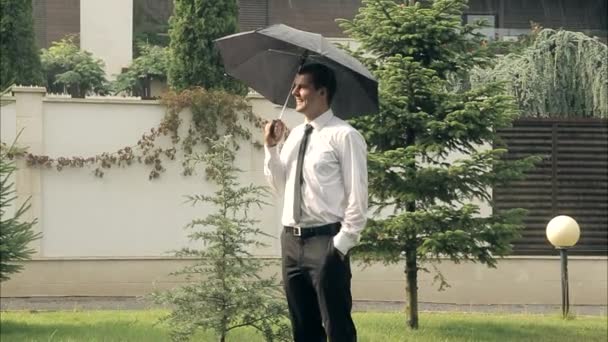 Uomo d'affari con ombrello sorride nel concetto di successo della pioggia estiva — Video Stock