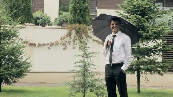 Hombre de negocios con paraguas sonriendo en el concepto de felicidad de lluvia soleada — Vídeos de Stock