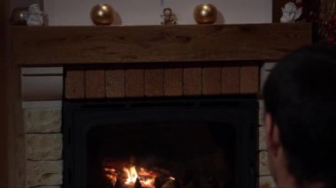 Bir şömine önünde oturan genç adam