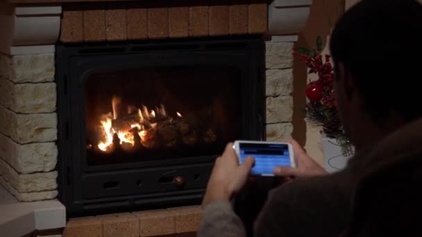 Joven está escribiendo un SMS delante de una chimenea concepto de comunicación — Vídeo de stock