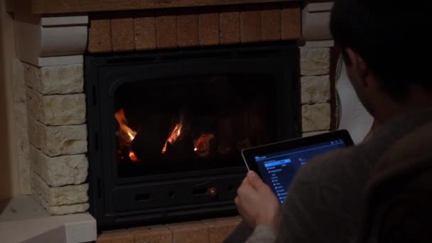 Man Is Using His Tablet In Front Of A Fireplace Technology and Home Concept — Stock Video