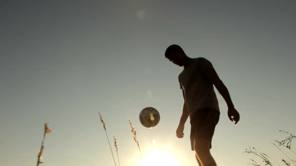 Młody mężczyzna piłka nożna gry na piękny zachód słońca — Wideo stockowe