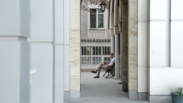 Молодой человек читает Библию на скамейке — стоковое видео