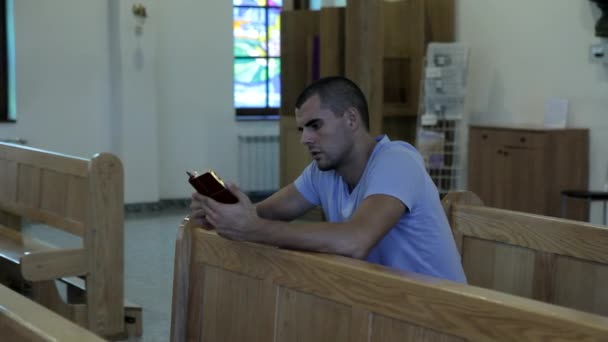 Joven leyendo la Biblia en una iglesia — Vídeo de stock