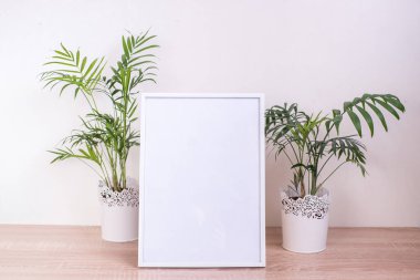 Ahşap masada beyaz portre çerçevesi modeli. Çiğnemeli modern seramik vazo. Beyaz duvar arka planı. İskandinav iç mimarisi. Dikey.