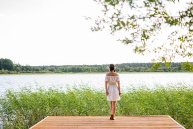 Bronzlaşmak ve tatilin tadını çıkarmak. Genç ve güzel bayan, ahşap sahilde kalın. 