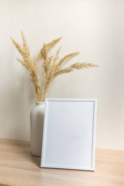 Portre çerçevesi ahşap masada kurumuş çiçeklerle süslenir.