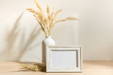 Portre çerçevesi ahşap masada kurumuş çiçeklerle süslenir.