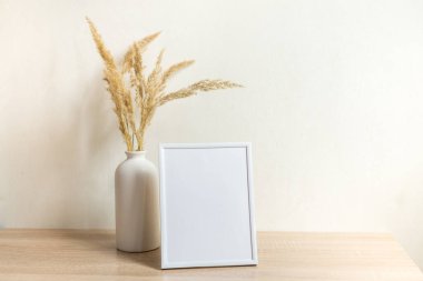 Portre çerçevesi ahşap masada kurumuş çiçeklerle süslenir.