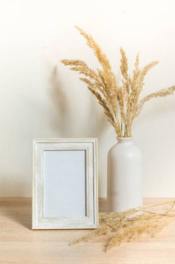 Portre çerçevesi ahşap masada kurumuş çiçeklerle süslenir.