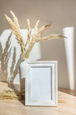 Portre çerçevesi ahşap masada kurumuş çiçeklerle süslenir.