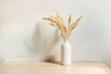 Portre çerçevesi ahşap masada kurumuş çiçeklerle süslenir.