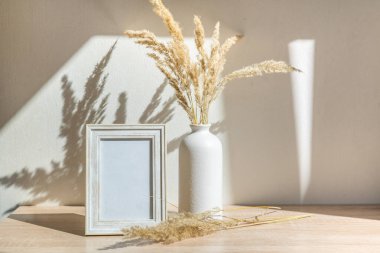 Portre çerçevesi ahşap masada kurumuş çiçeklerle süslenir.