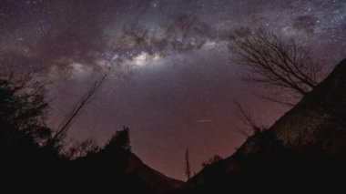 Şili 'deki Valle del Elqui dağları arasında kayan yıldızlarla dolu bir vadi üzerinde hareket halindeki bir Samanyolu' nun zaman kayması.