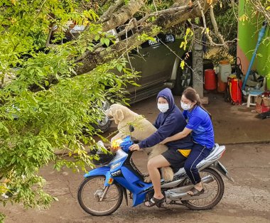 Büyük bir köpek ve motosiklette maske takan iki kız. Fak Tha, Utarradit, Tayland, 7 Nisan 2021