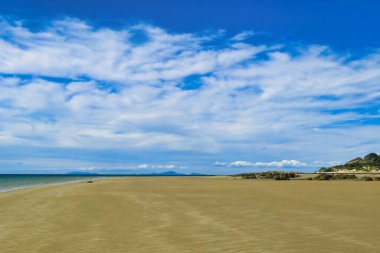 Avustralya 'nın kuzeydoğu Tazmanya bölgesindeki Waterhouse Koruma Alanı' nda geniş, ıssız ve rüzgârlı bir sahil. Uzakta Flinders Adası 'nın tepeleri.
