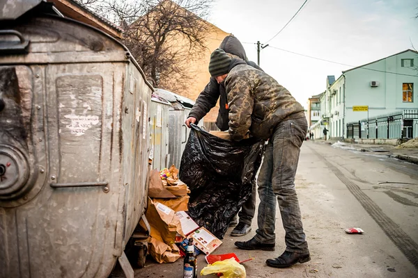 Poltava, Ukrayna - 18 Şubat 2016: iki genç erkekler diğer çöp geri dönüşüm için kağıt toplama. Ülkede enflasyon üç kez para maliyeti azalttı.
