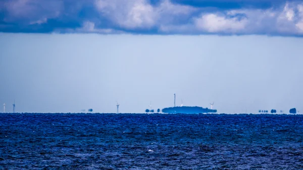 Fata Morgana (mirage) wybrzeża z turbin wiatrowych na nim — Zdjęcie stockowe