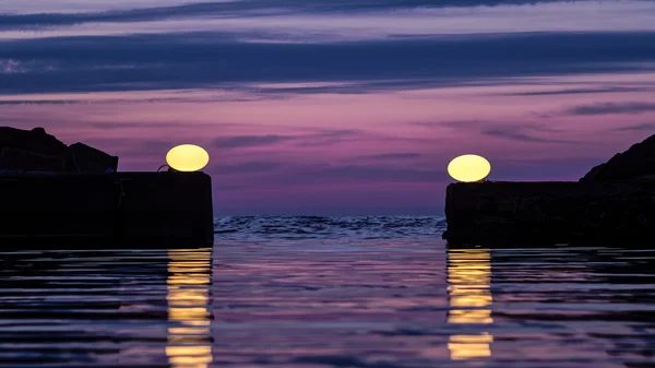 To lys placeret kunstnerisk nær indgangen en lille havn Stock-billede