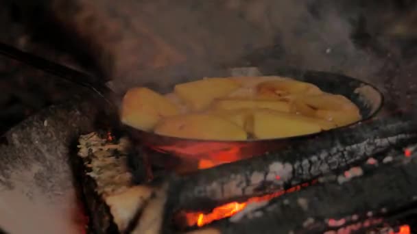 Смажити картоплю в маслі за допомогою сковороди з вуглецевої сталі безпосередньо на відкритому вогні табору — стокове відео
