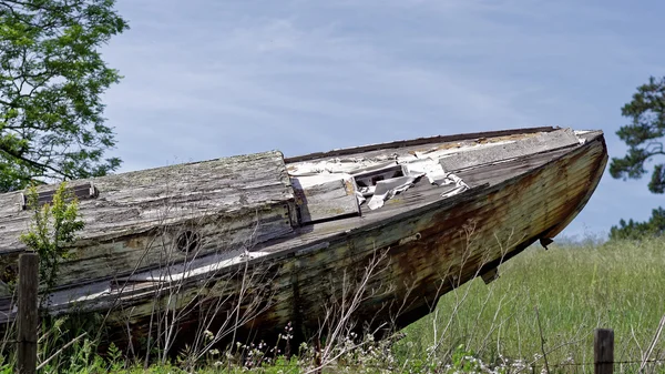 Old wooden boat dragged onto a field — Stock Photo, Image