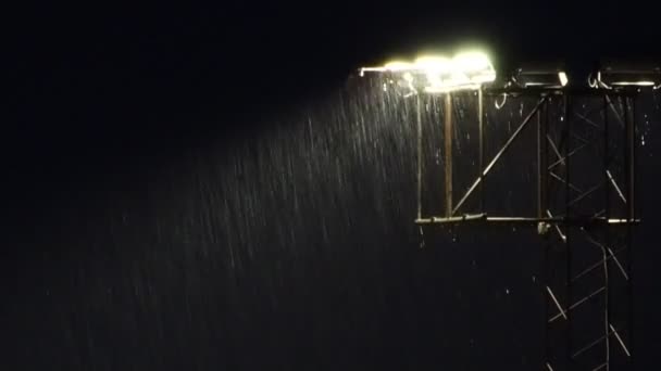 Het stadion breedstralers 's nachts tijdens een zware regendouche. — Stockvideo