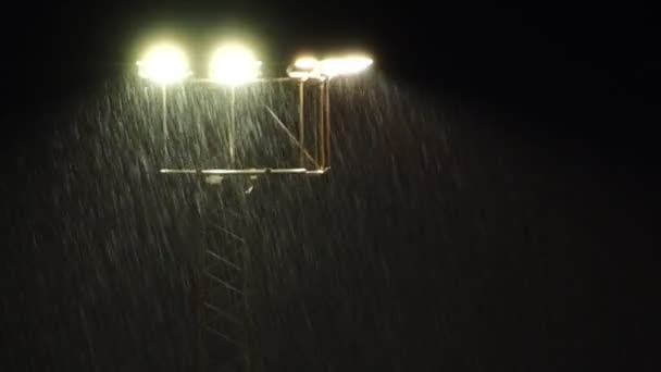Stadion reflektorok éjszaka során a zajos, esőzuhany. — Stock videók