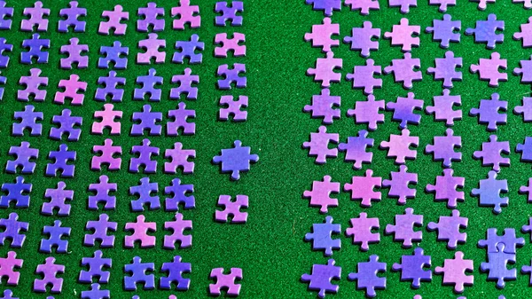 Peças de quebra-cabeça roxo classificados em uma mesa verde — Fotografia de Stock