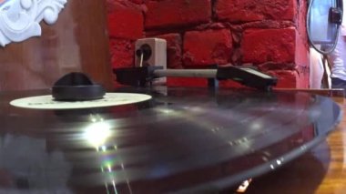 Vinyl record is spinning in the turntable against the background of a red wall