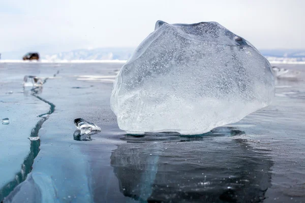 A piece of ice on the surface of the blue frozen Lake Baikal with car at background — Stock Photo, Image