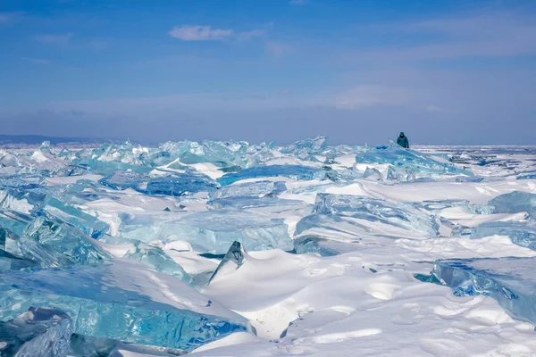 Campo de hummocks transparentes azuis no lago congelado Baikal. Silhueta de mulher ambulante no céu azul . — Fotografia de Stock