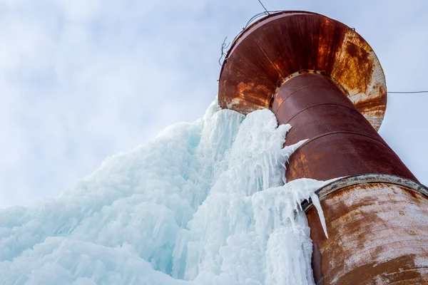 stock image Rusty water tower covered with blue ice at winter time