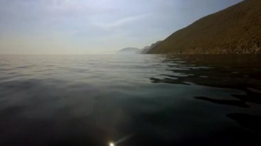 Rock sahil arka plan ve güneşli yaz gün hafif pırıltılar Göl yüzeyinde seyahat