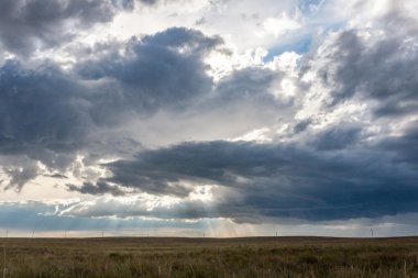 Güneş ışınları altında alan electrici ile kara bulutlar geçiyor