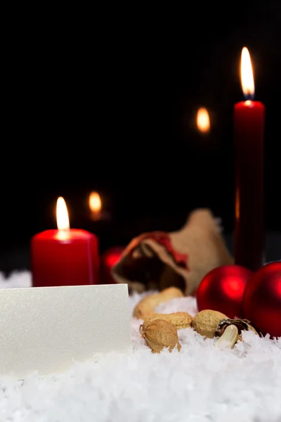 Red baubles, candles, gunny bag, blank card, artificial snow — Stock Photo, Image