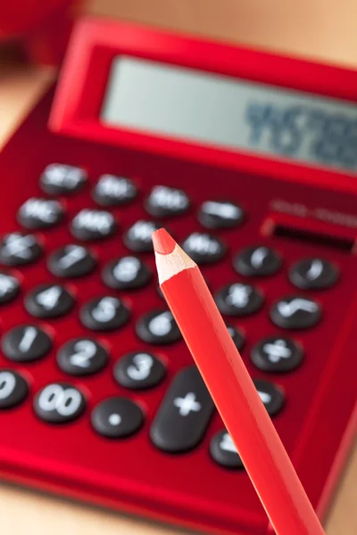 Red calculator, red pencil in foreground — Stock Photo, Image