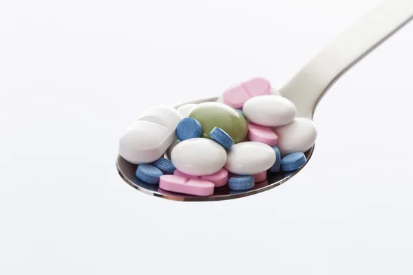 Змішані таблетки в ложці на білому тлі — стокове фото