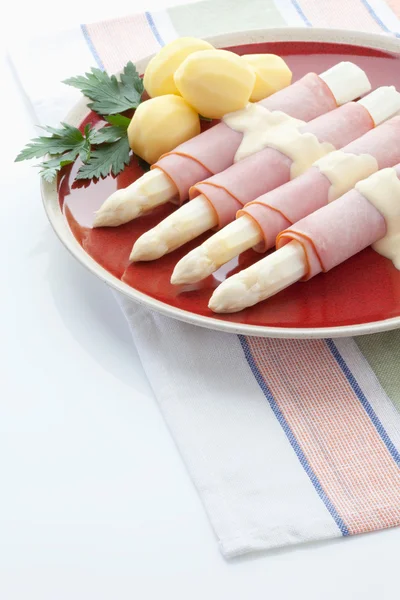 Asparagus,potatoes,ham and parsley in plate on white background — Stock Photo, Image