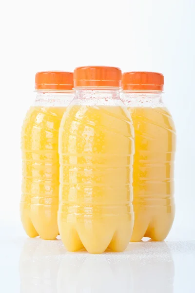 Botellas de zumo de naranja sobre fondo blanco, primer plano — Foto de Stock