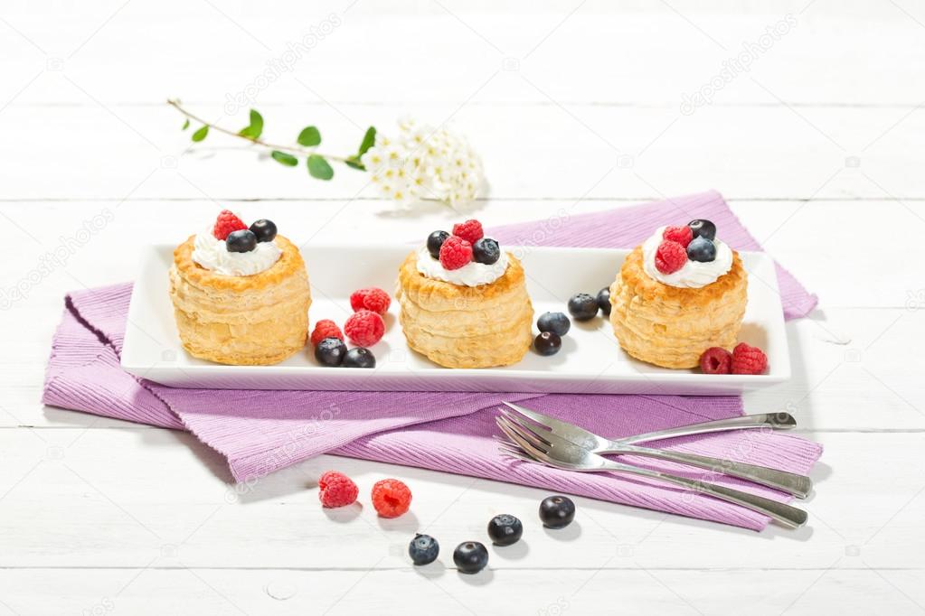 Puff pastries with vanilla-icecream and cream, blueberries and r