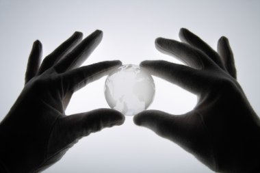 Pamuk eldiven karşı beyaz cam küre tutan insan eliyle 