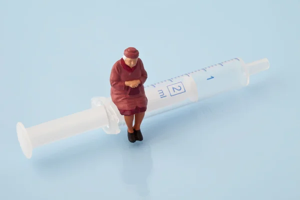 Female figurine sitting on syringe — Stock Photo, Image