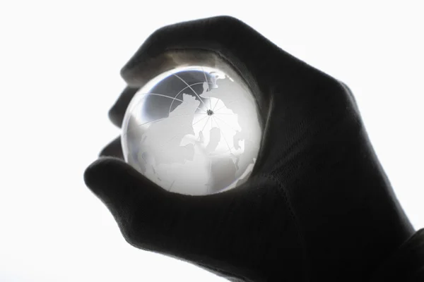 Mão humana com luvas de algodão agarrando globo de vidro contra branco — Fotografia de Stock
