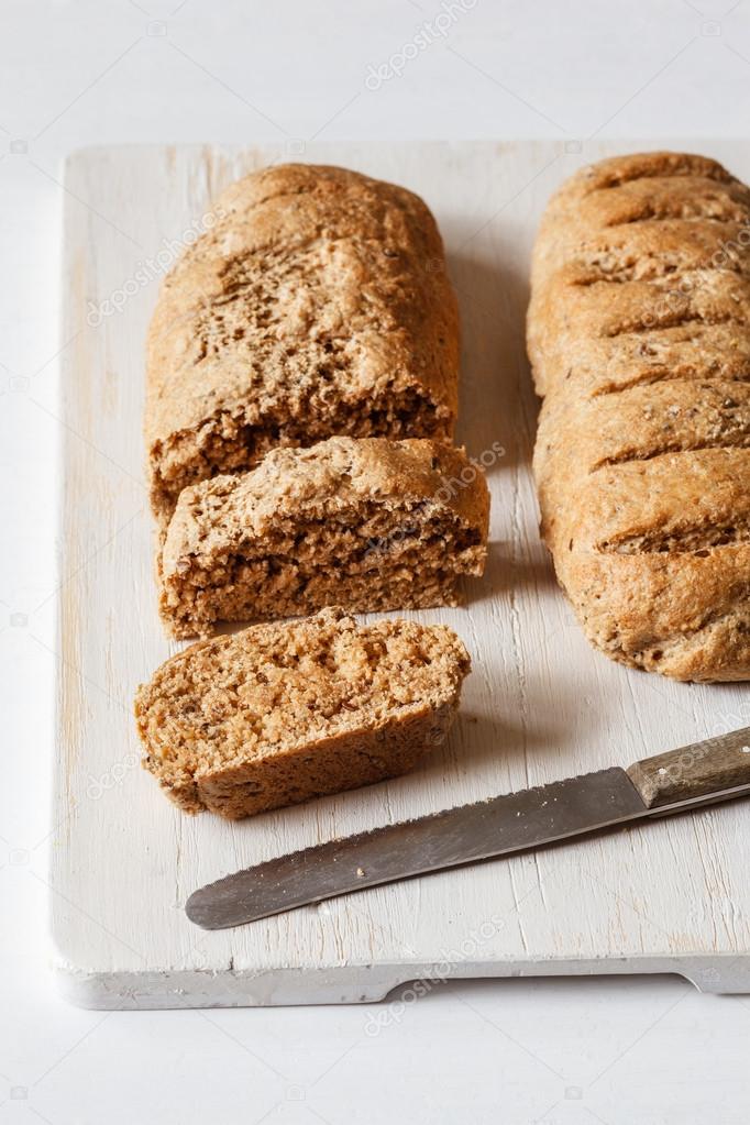 Wholemeal spelt baguettes on chopping board, knife